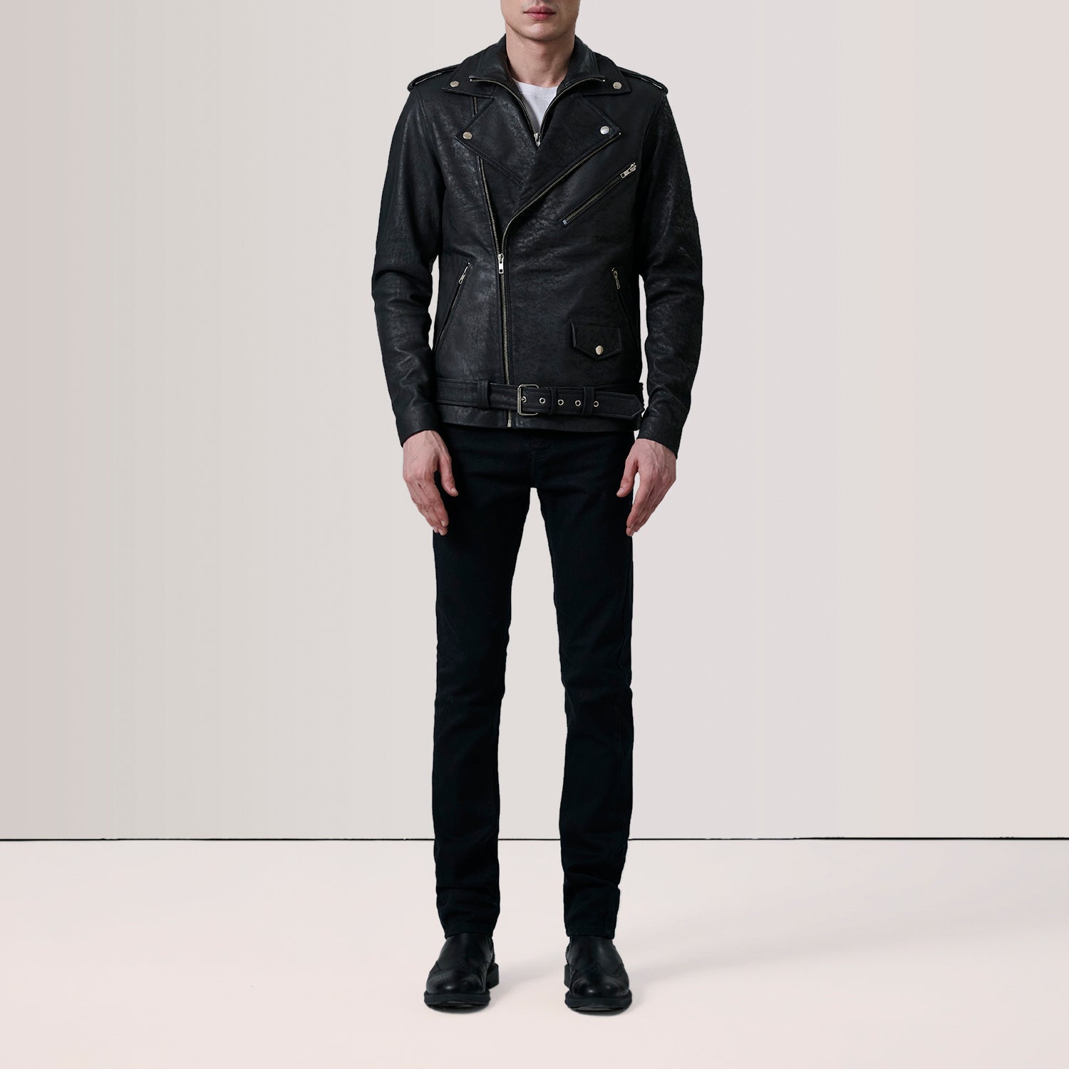 Person wearing a black leather jacket and pants on a plain background