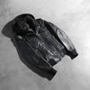 Detailed view of the snug rib knit cuffs and the dual chest and waist utility pockets on the front of the jacket.