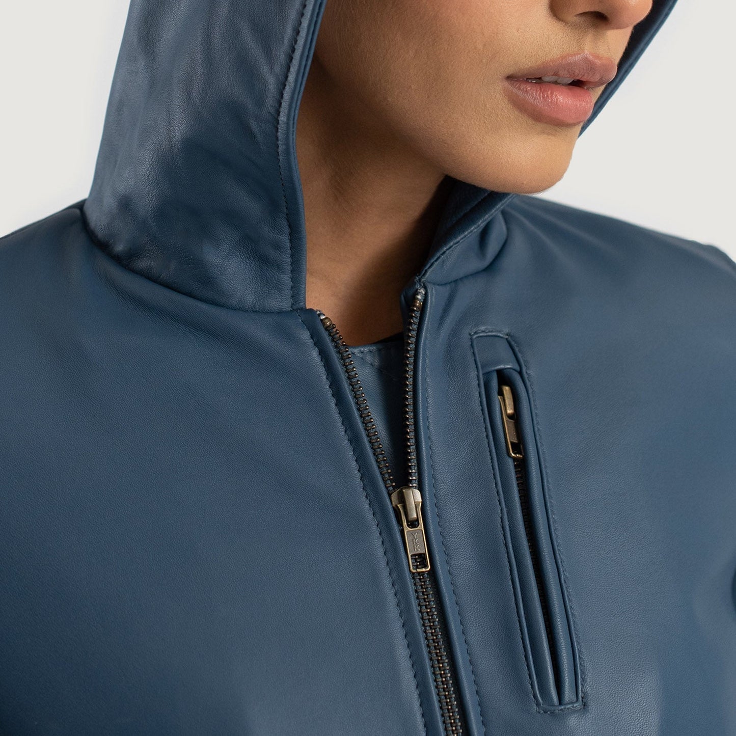 Close-up of a person wearing a blue jacket with a hood on a plain background