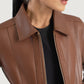 Cinematic side angle view of the brown classic collar leather jacket, capturing the subtle sheen of the hide under warm, natural lighting.