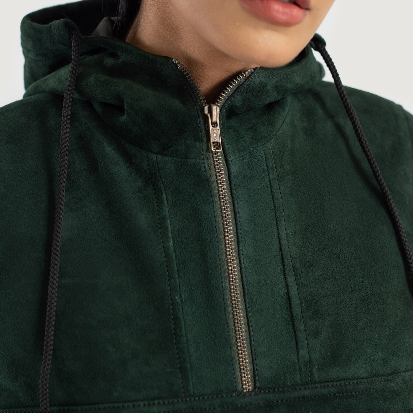 Close up of the partial front zipper closure and hardware on the green suede pullover.